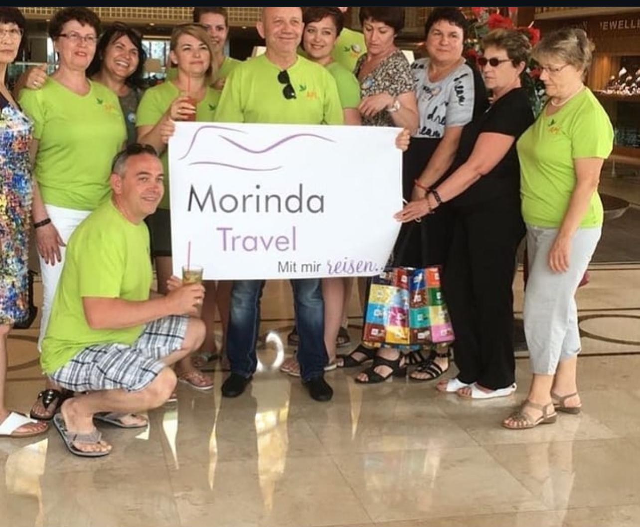 Reisegruppe in grünen Shirts mit dem Morinda-Travel-Schild