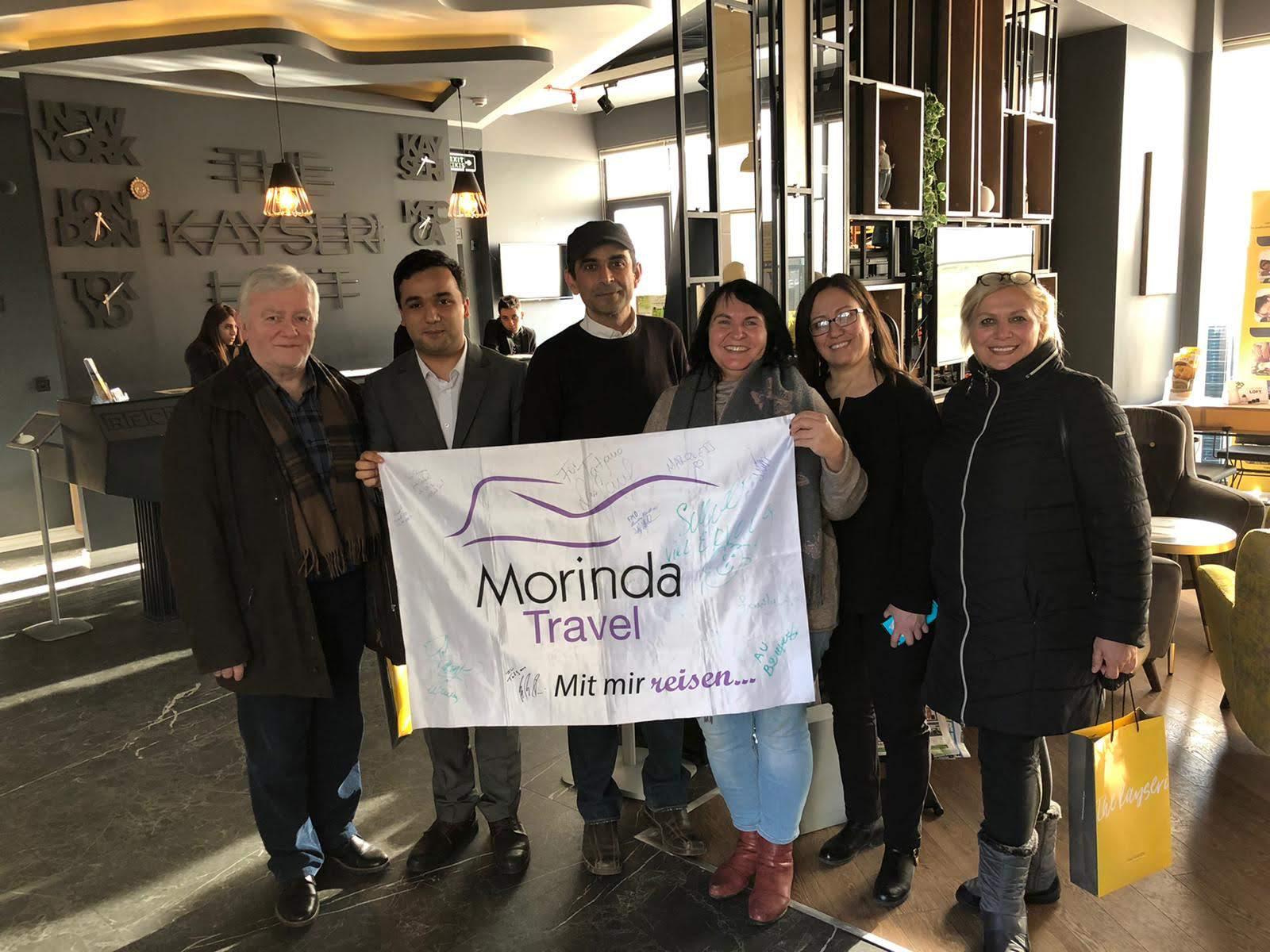 Gruppe mit der Morinda-Travel-Fahne in einem Hotel in Kayseri